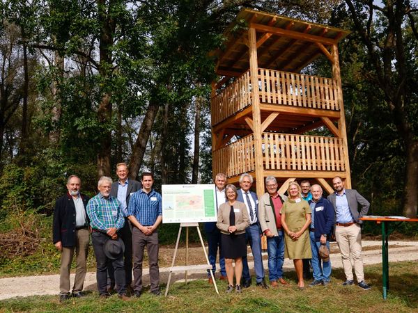 Menschen stehen vor dem neuen Aussichtsturm aus Holz im Wiesenbrütergebiet Thonstetten, Landkreis Freising.