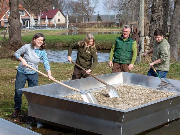 Rebecca Oechslein, Biologin bei der Heinz Sielmann Stiftung, und das Team der Fischerei Köllnitz befüllen die neuen Brutinseln mit einem Kies-Sand-Gemisch.